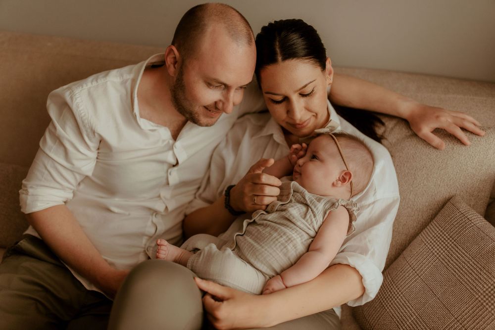 Family cuddles together on neutral colored couch during lifestyle photoshoot.