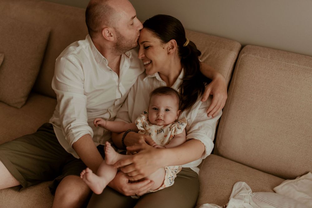 Warm family portrait on couch with soft natural lighting.