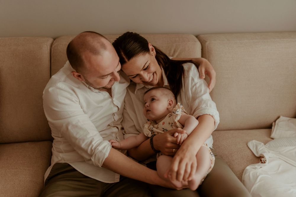 Intimate family moment captured in warm sepia tones on couch.