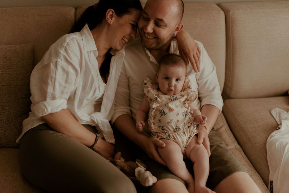 Loving family cuddles together during an indoor lifestyle photoshoot with muted tones.