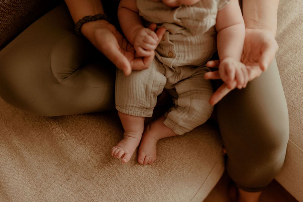 Close-up photography of baby details and family interaction in muted tones.