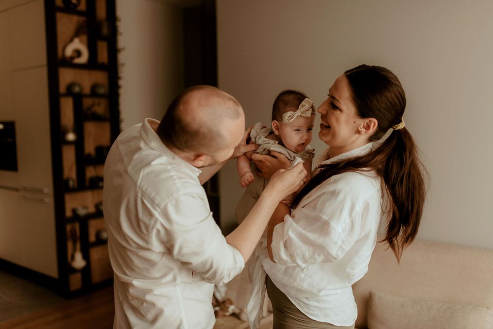 Family lifestyle photography session with parents and infant in neutral tones.