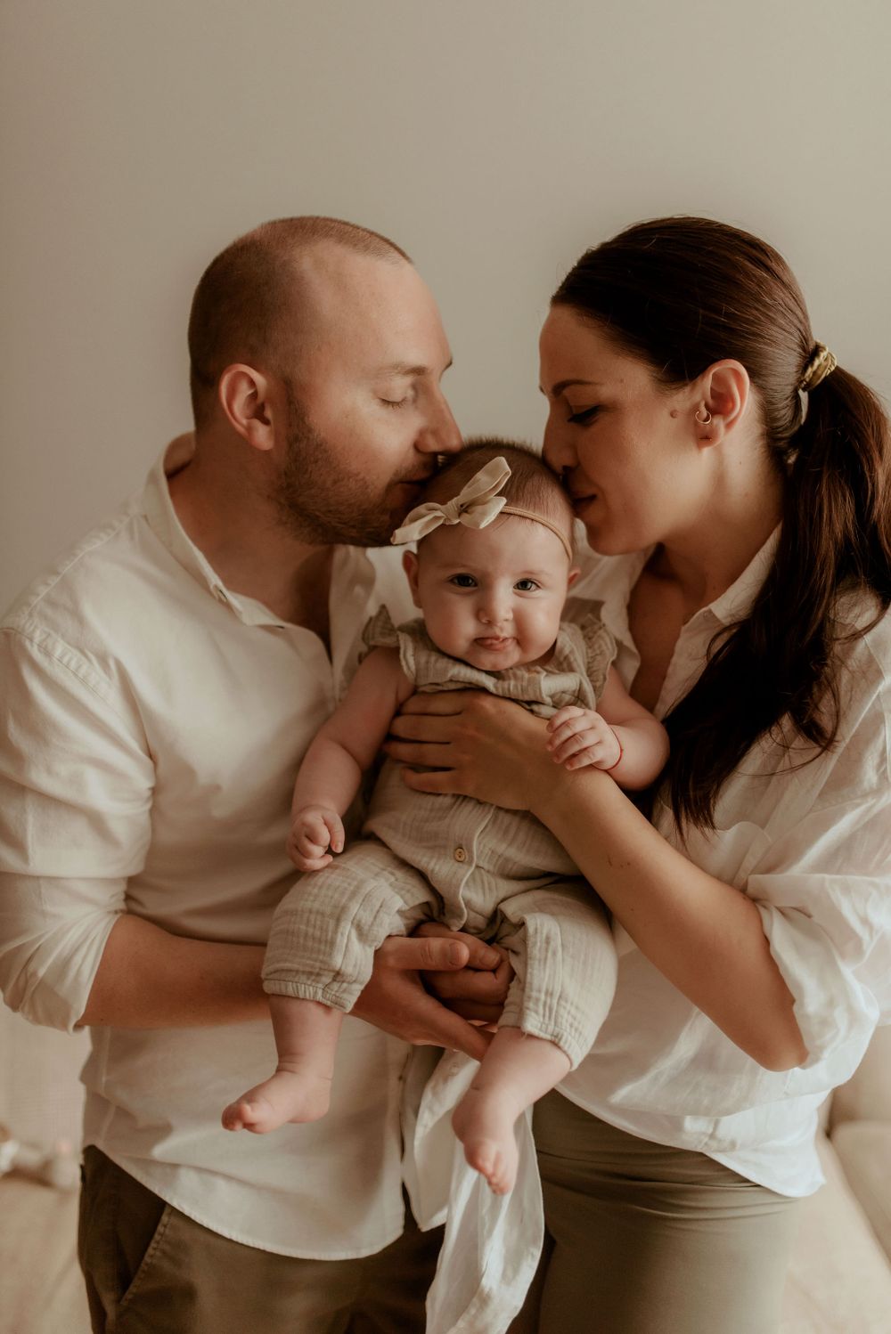 Tender family moments captured in soft, neutral tones during an indoor photo session.