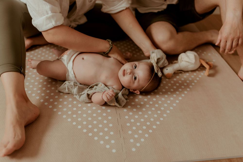 Family lying on polka dot blanket during intimate photo session.