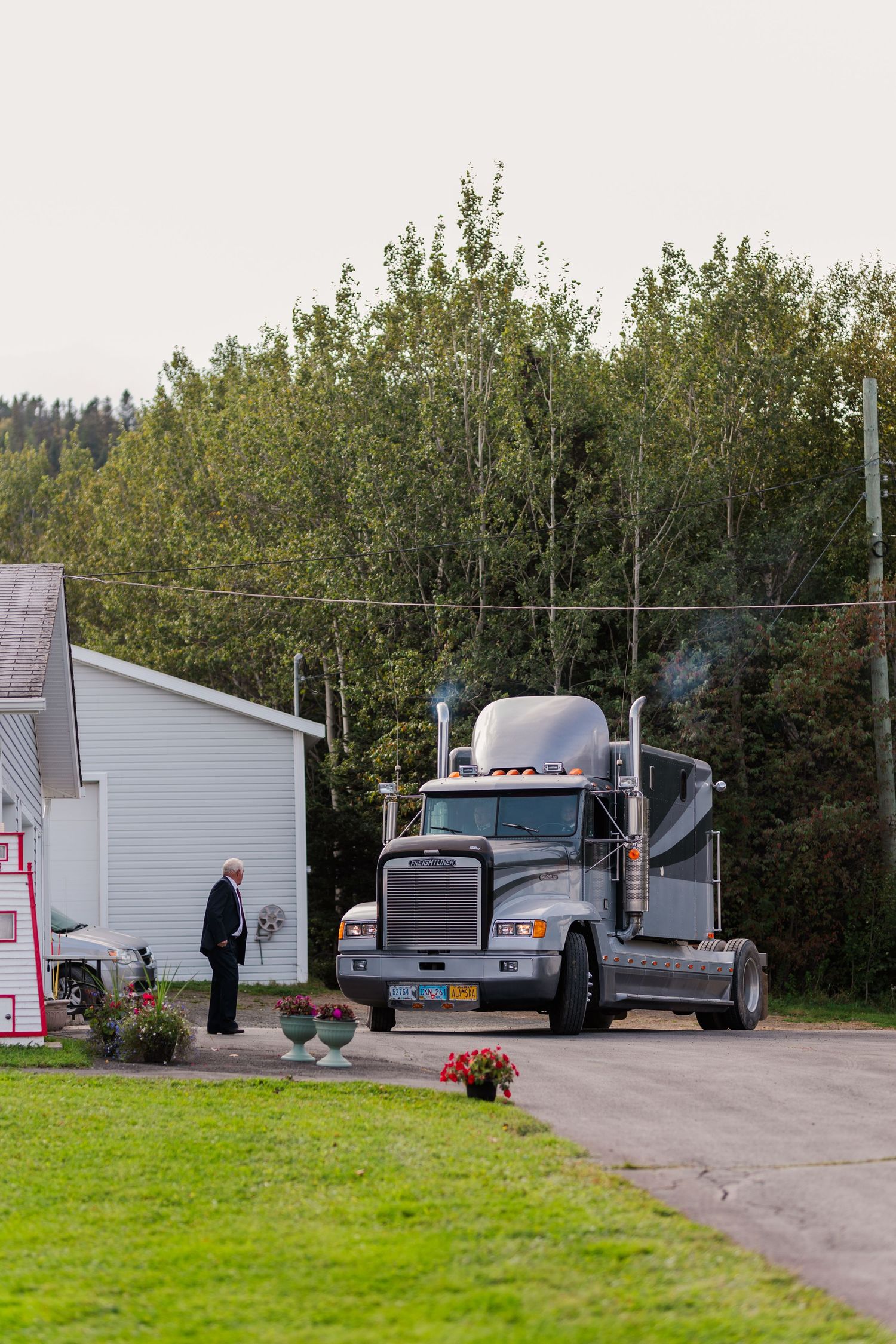 Semi trucks parked outside mobile homes on grassy property.