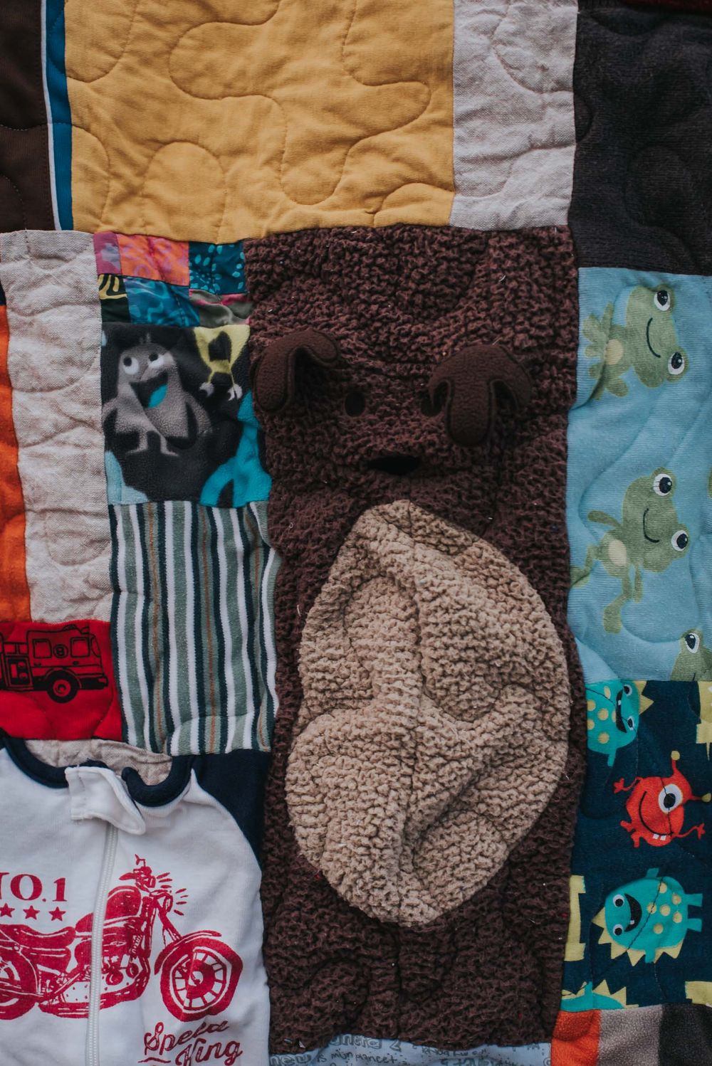 Memory quilt with a fuzzy bear sleeper incorporated into a patch.