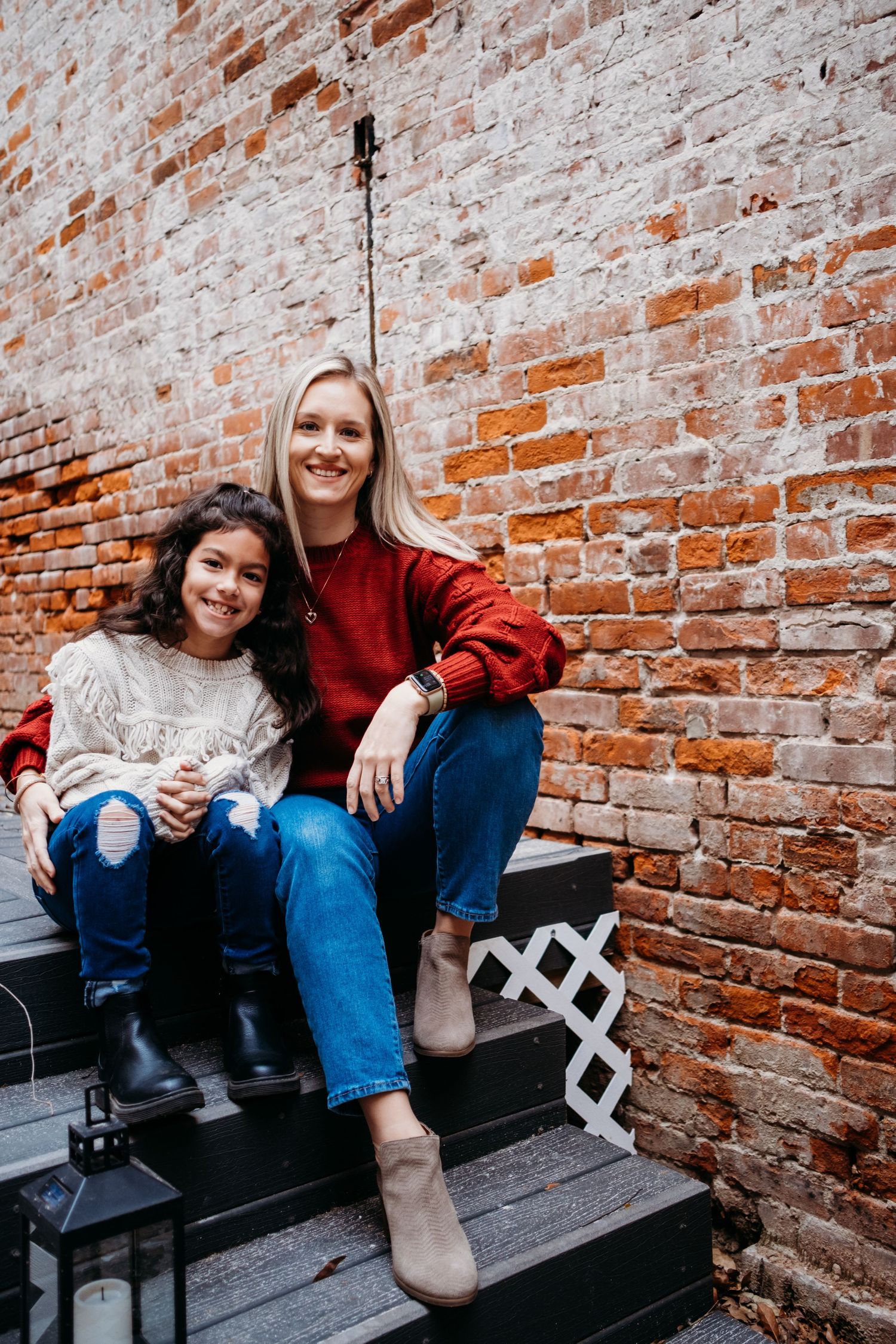 A mom and daughter sit smiling in downtown St. Joseph, Missiouri for a family photography session.