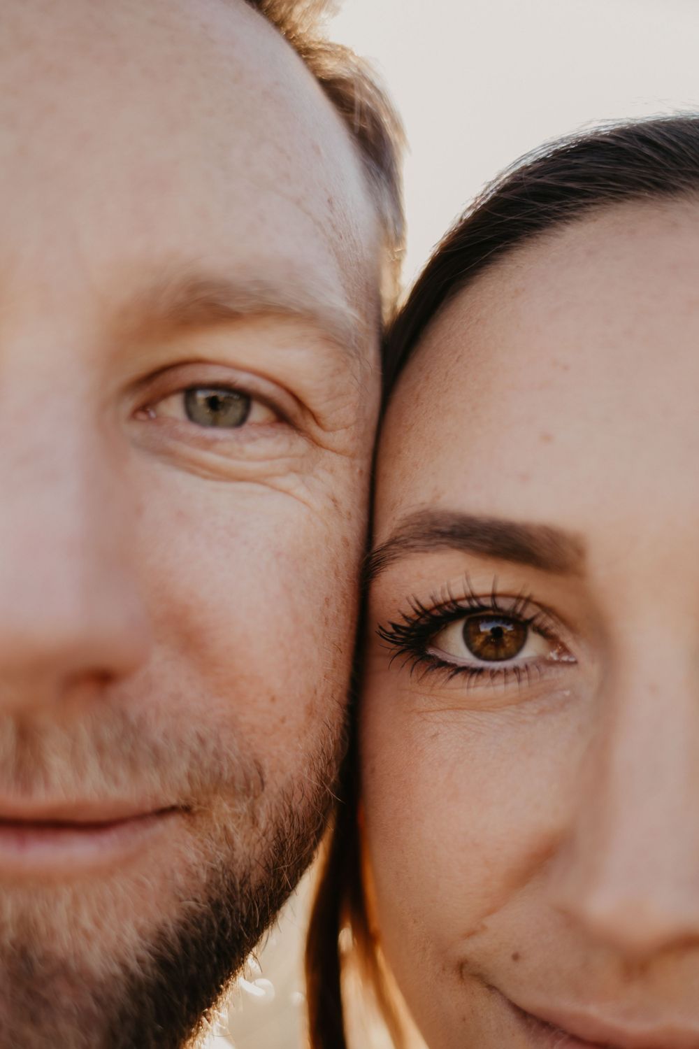 An intimate close-up portrait showing half of two faces together in warm lighting.