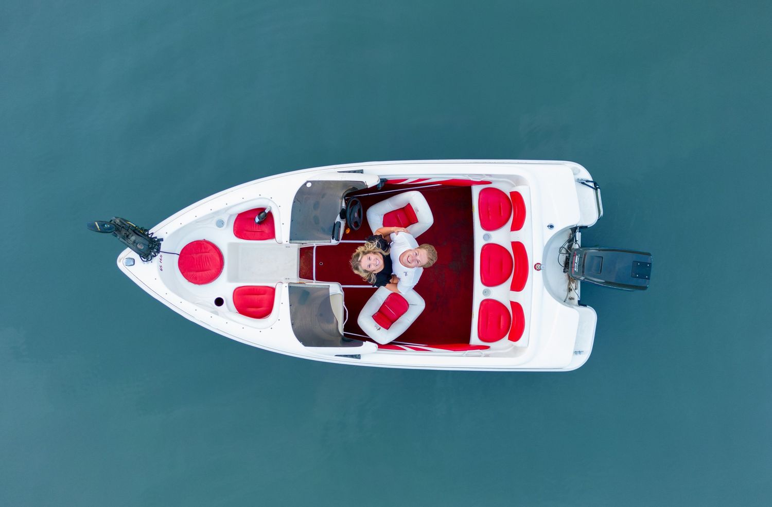 Aerial view of white speedboat with red seats on turquoise water.