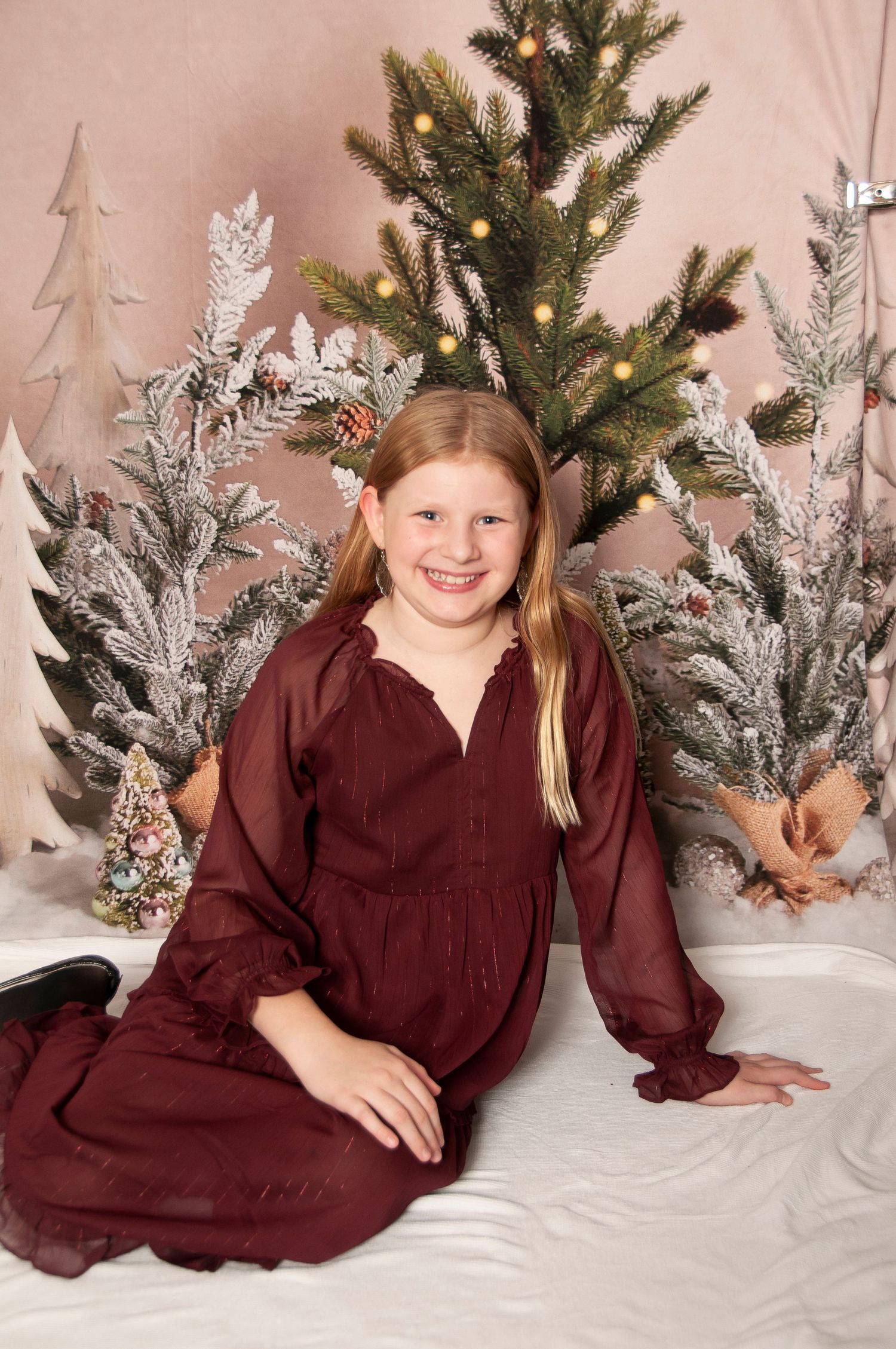 Young girl in holiday outfit with tree backdrop