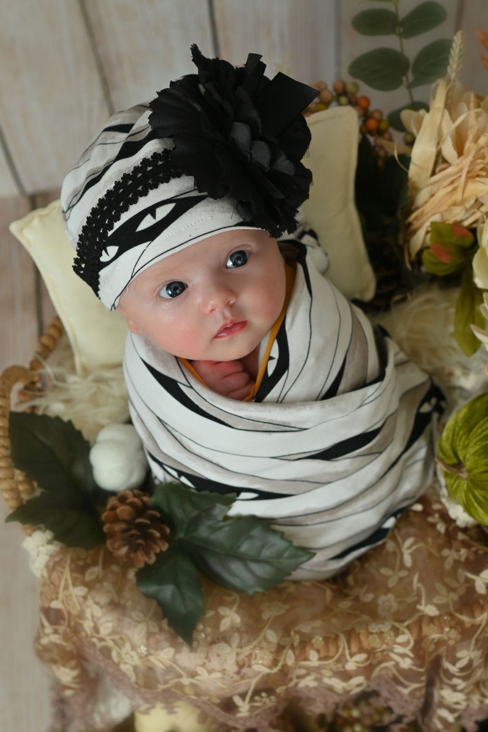 Baby wrapped in black and white striped fabric with matching flower headpiece.