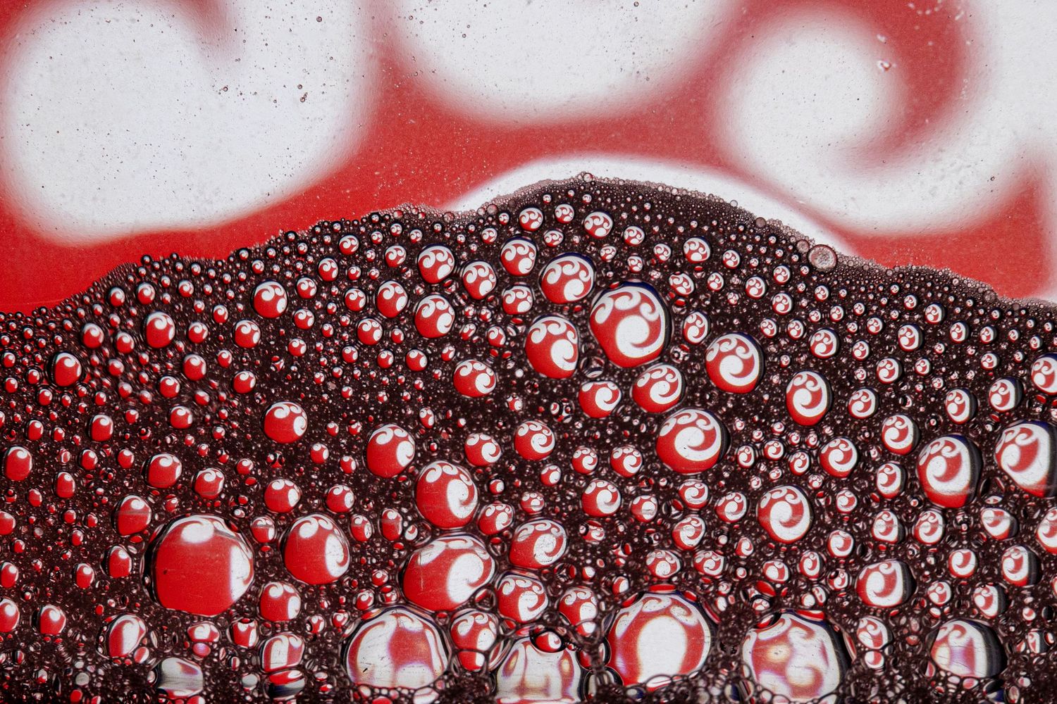 Scarlet bubbles dance over a milky surface, creating a bold and textured liquid landscape.