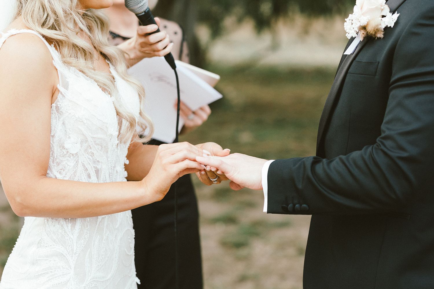 Wedding couple holding hands while exchanging rings during their ceremony.