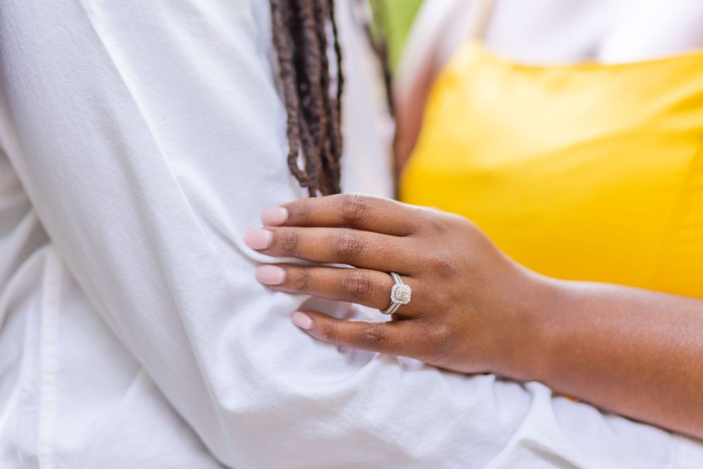 A close-up shot showcasing an engagement ring with a white and yellow outfit in view.