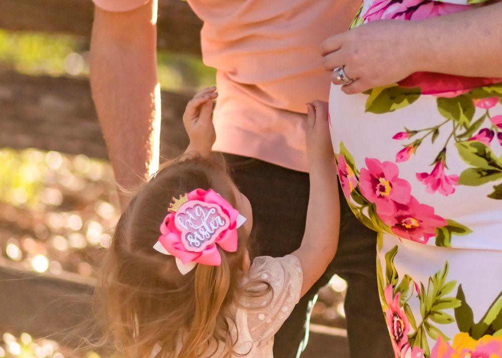 A tender family moment captured in warm sunlight with floral details.