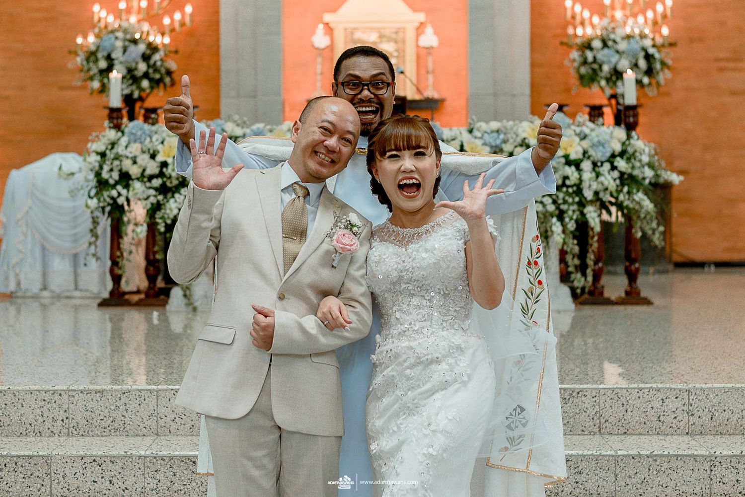 Wedding party posing together on stairs with orange backdrop and floral decorations.