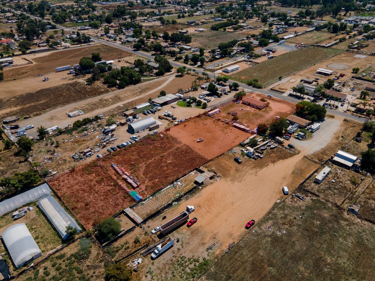 Aerial view of rural commercial development site with cleared red dirt lots and scattered structures.