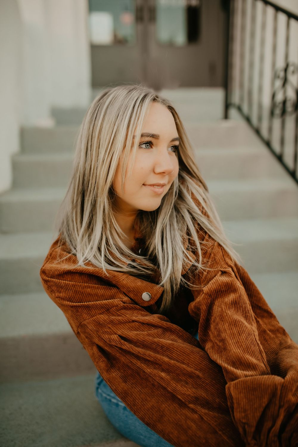 Closeup portrait in warm autumn tones featuring a brown corduroy jacket and flowing blonde hair.