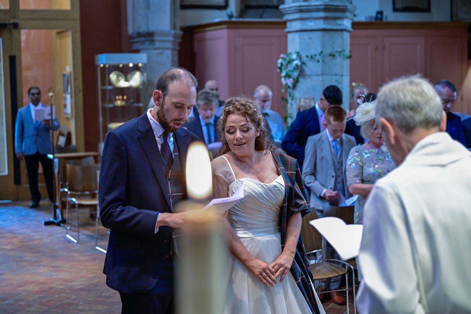 Indoor wedding ceremony scene with candle light in historic building interior.