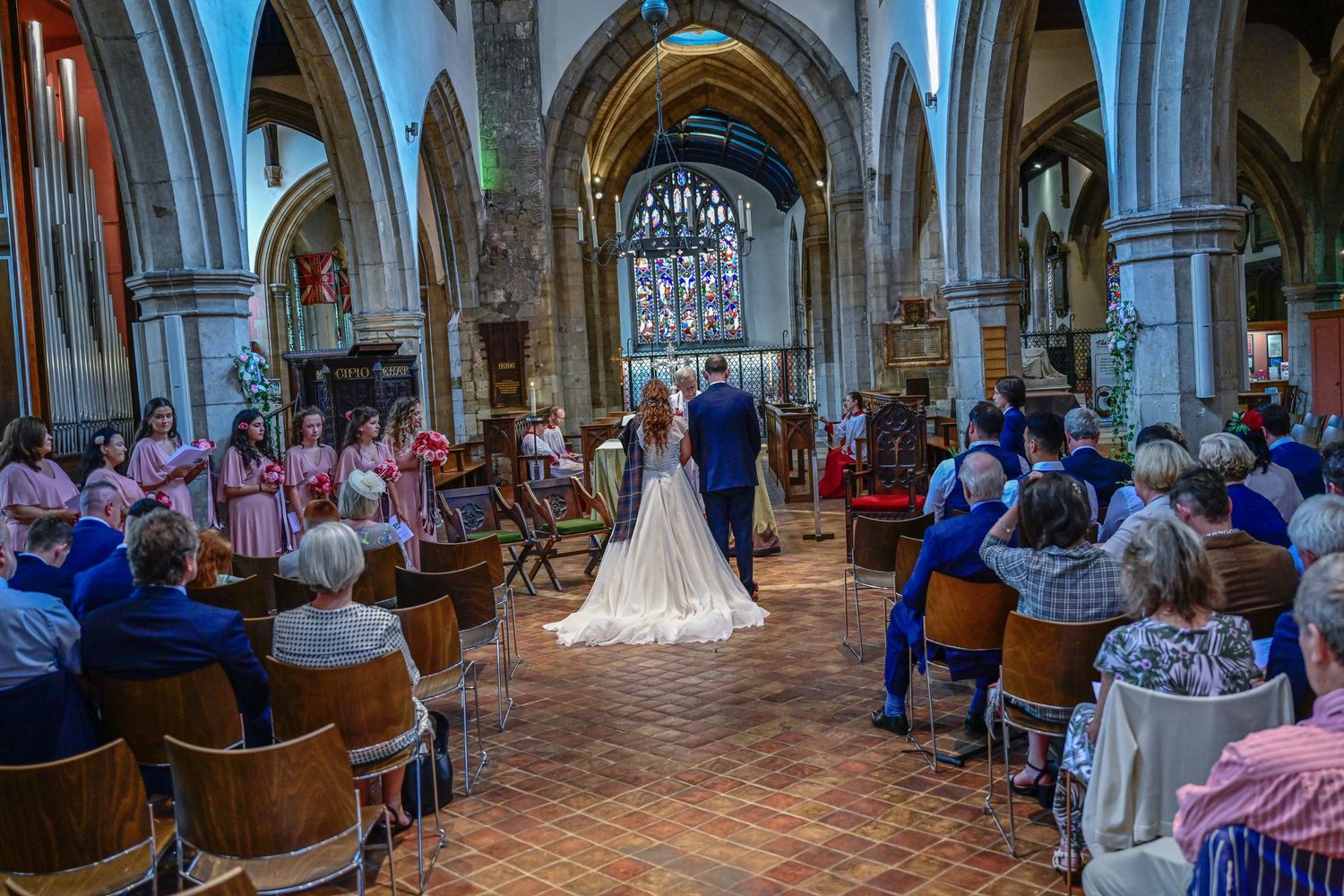 Wedding ceremony taking place in a historic stone church with vaulted arches and stained glass windows.