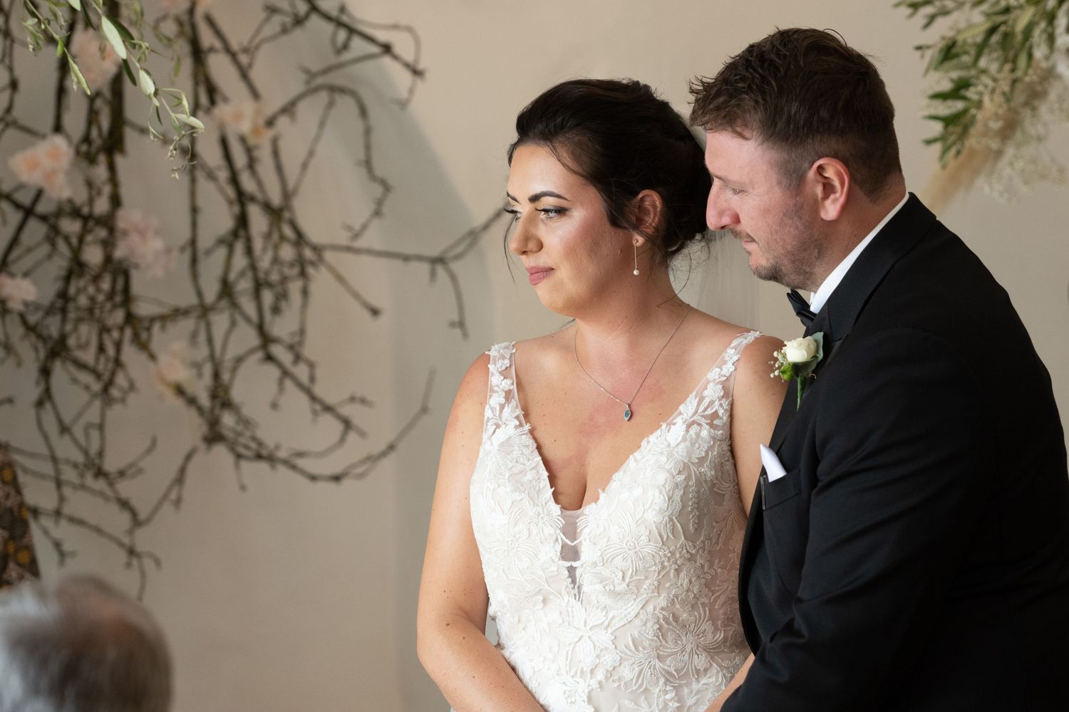 An intimate wedding ceremony moment underneath natural branch decorations.