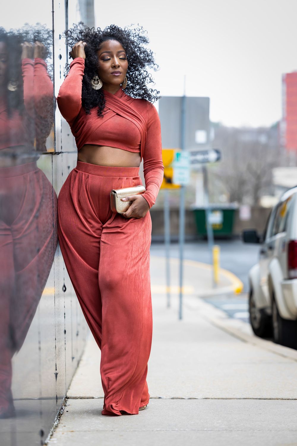 A fashionable look featuring a rust-colored crop top and wide-leg pants ensemble on an urban street.