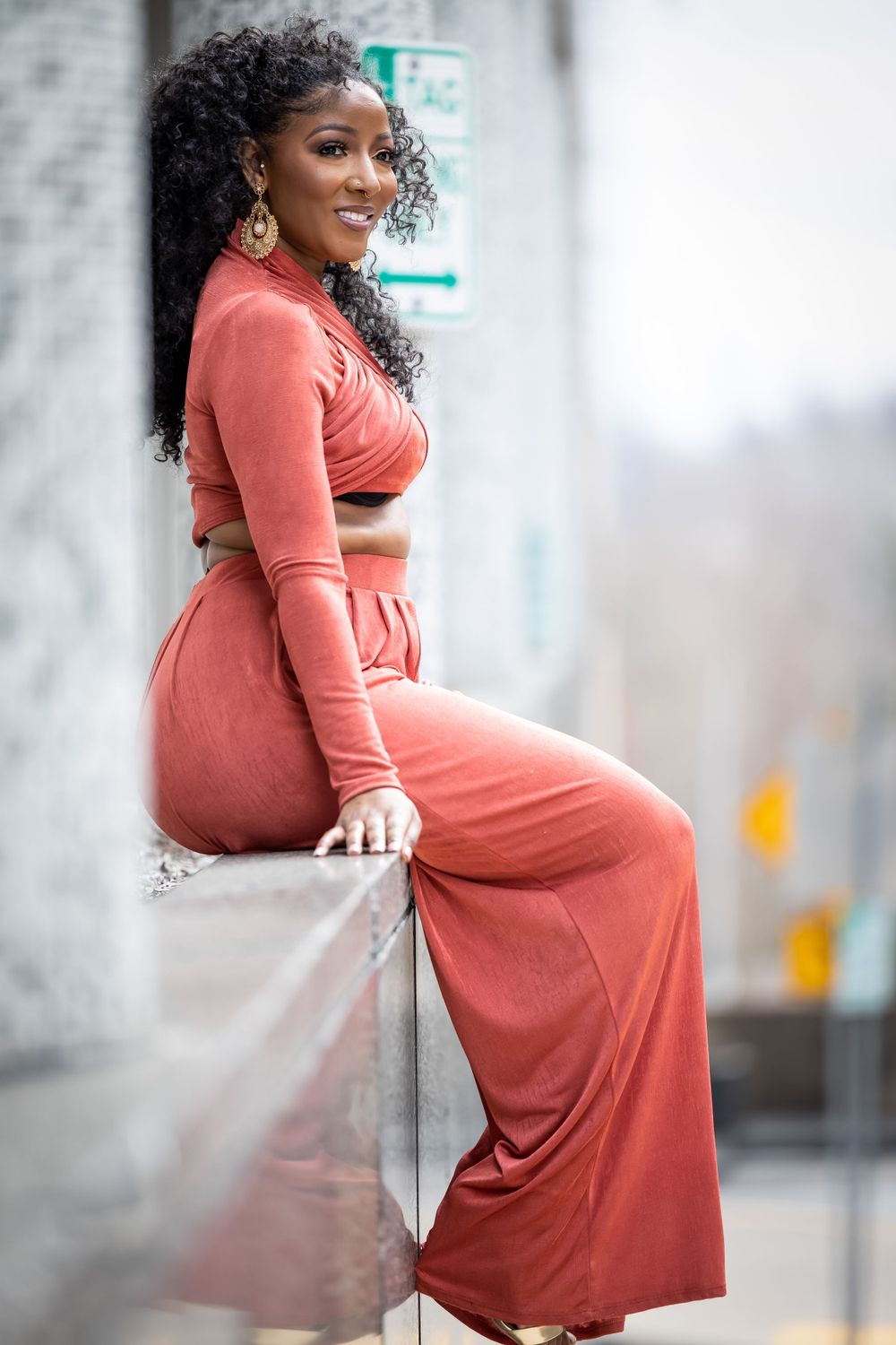 Sophisticated coral loungewear ensemble photographed in urban architectural setting.