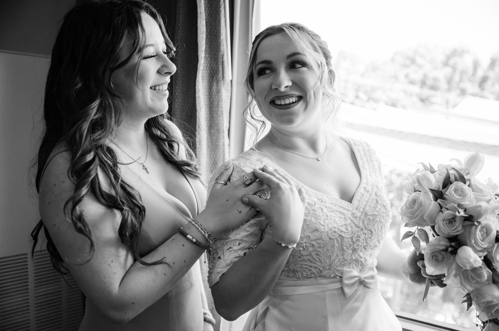 Candid black and white photo capturing joyful moment during wedding preparations.