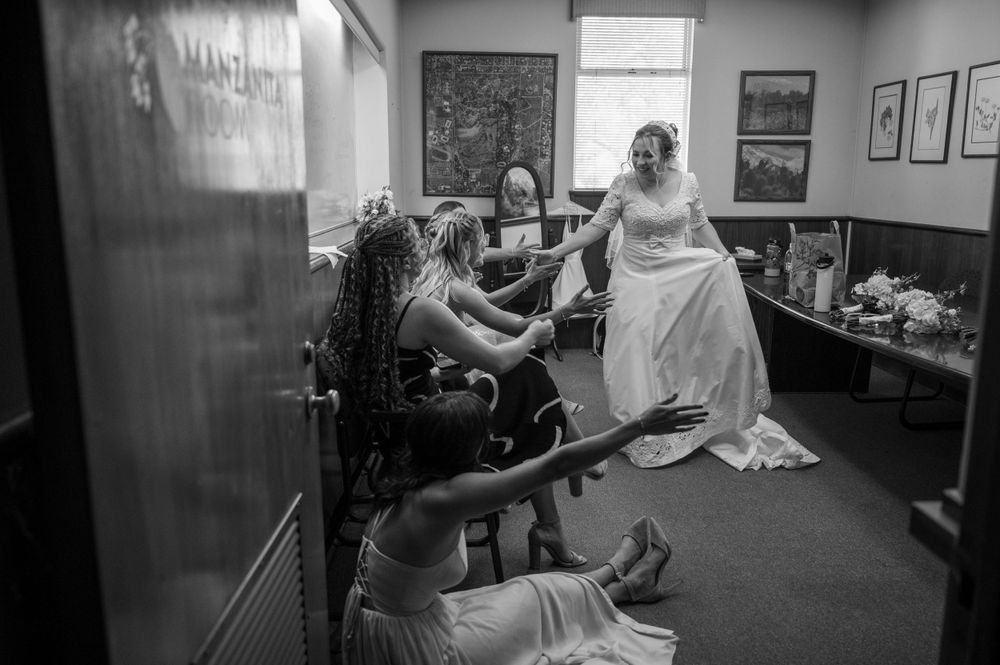 Black and white photo showing final wedding dress adjustments in preparation room.