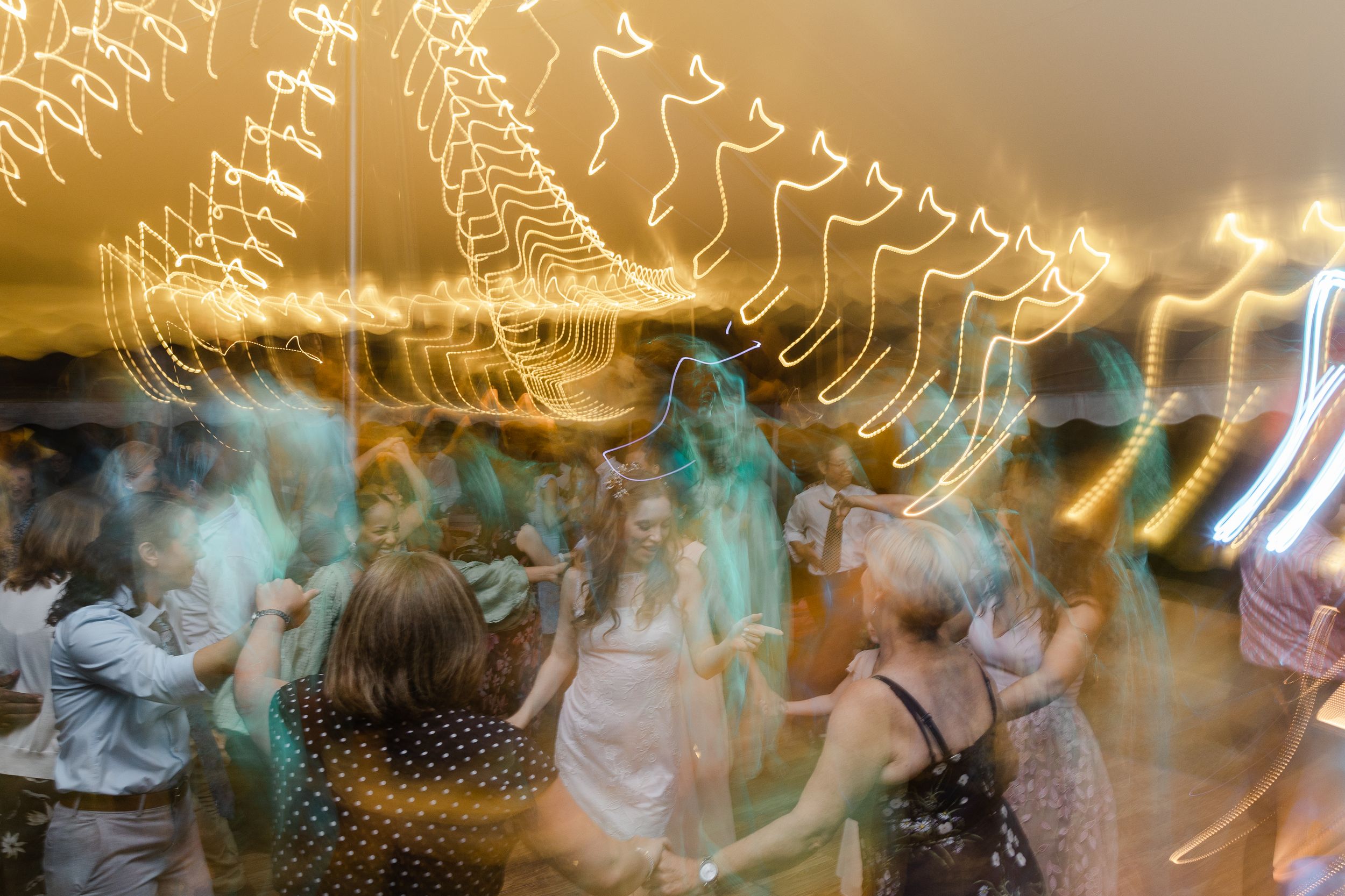 Motion-blurred wedding reception dance floor with streaking lights creating abstract patterns.