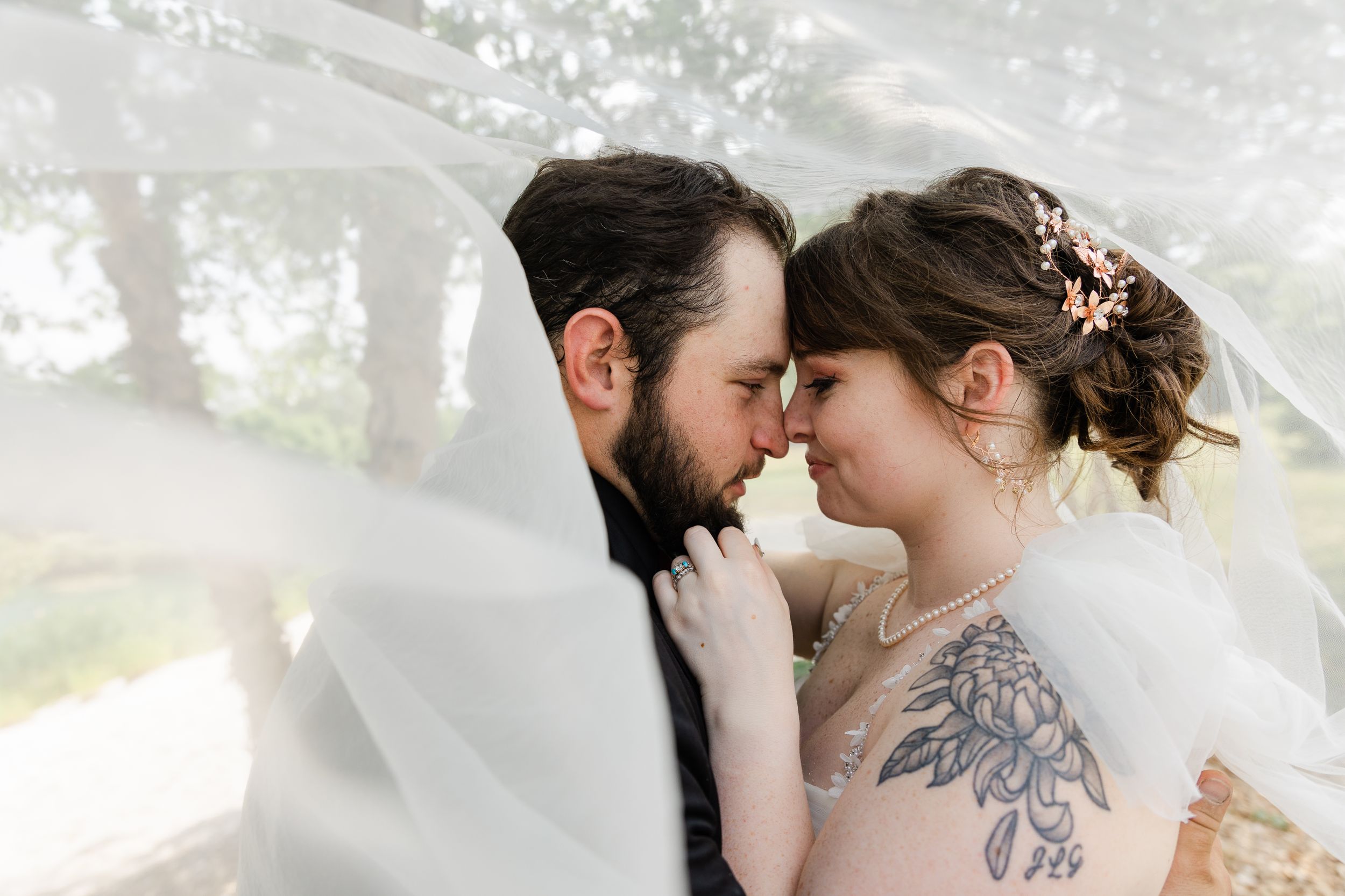 A tender wedding moment captured through delicate veil fabric.
