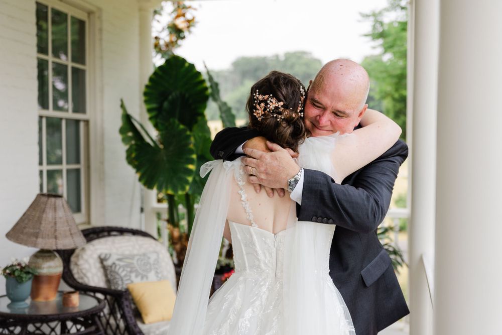 Emotional moment shared on a white porch during a wedding day.