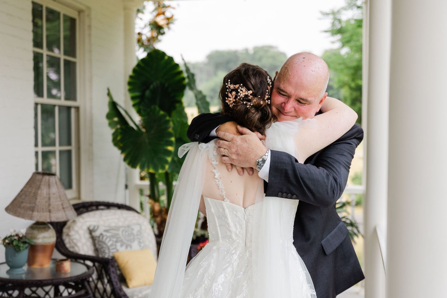 Emotional moment shared on a white porch during a wedding day.