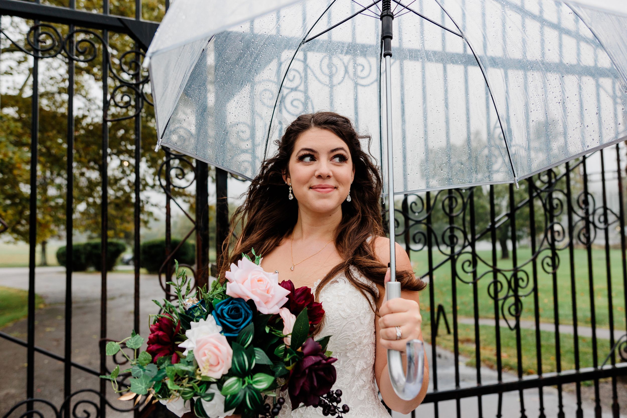 Beautiful bridal portrait at ornate iron gates with flowers and elegant architecture.
