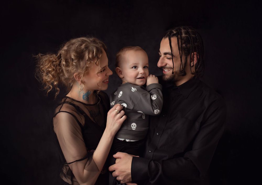 Dramatic family portrait with dark background and moody lighting.