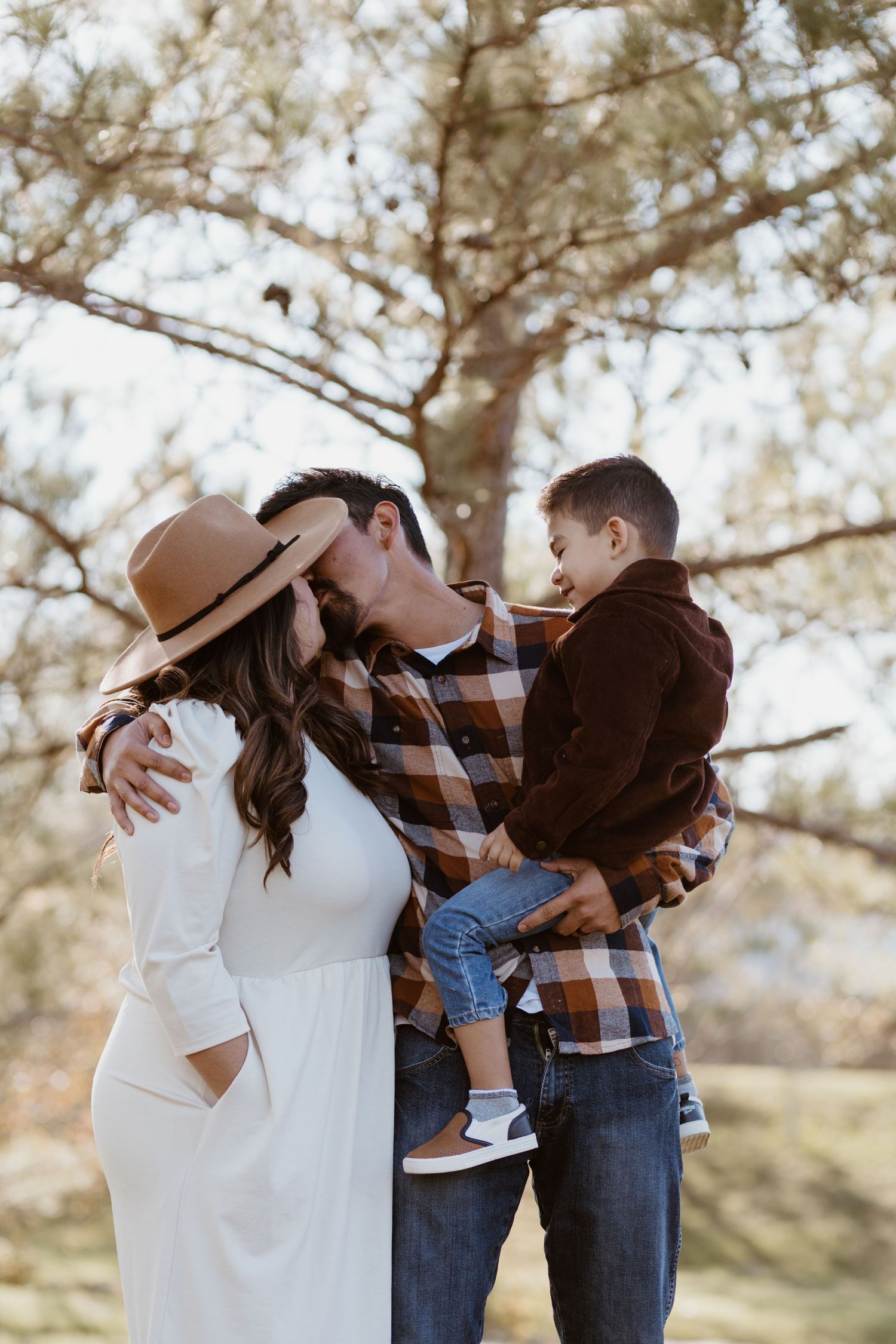 mom and dad kissing in front of child family photography