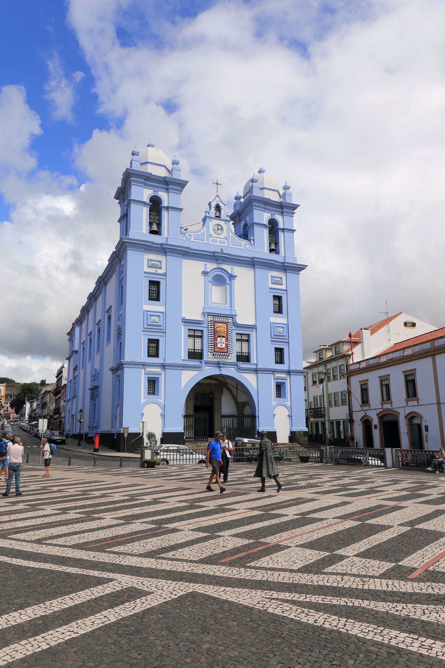 Blue and white church facade with twin bell towers in a Portuguese town square.