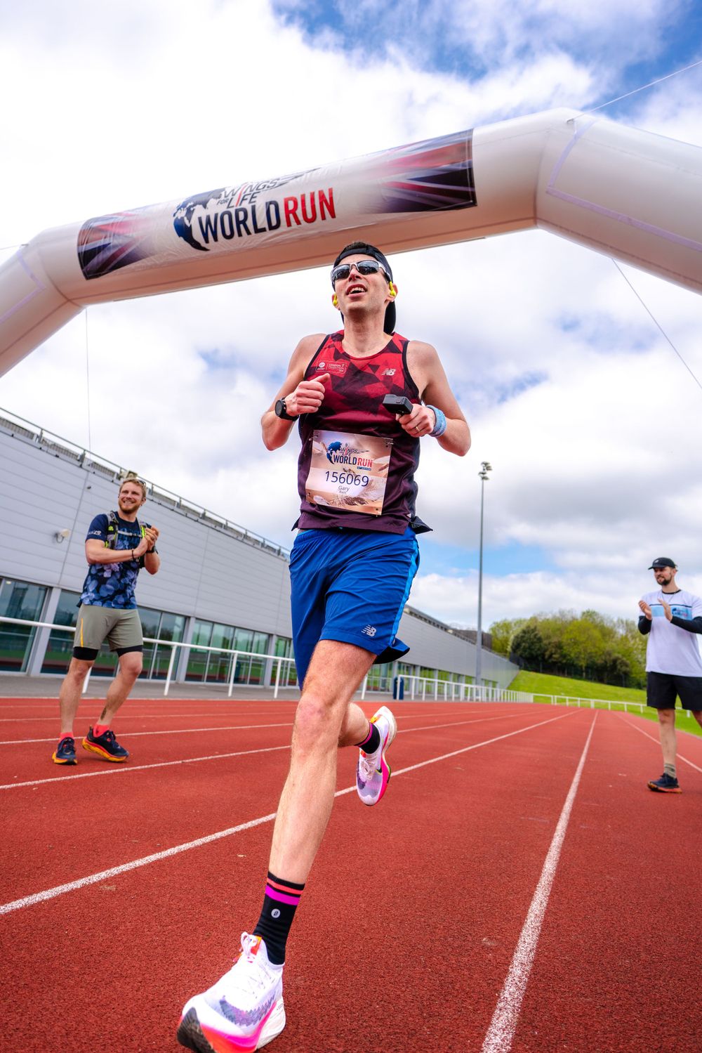 Runner passing under Wings for Life World Run inflatable arch on a track.