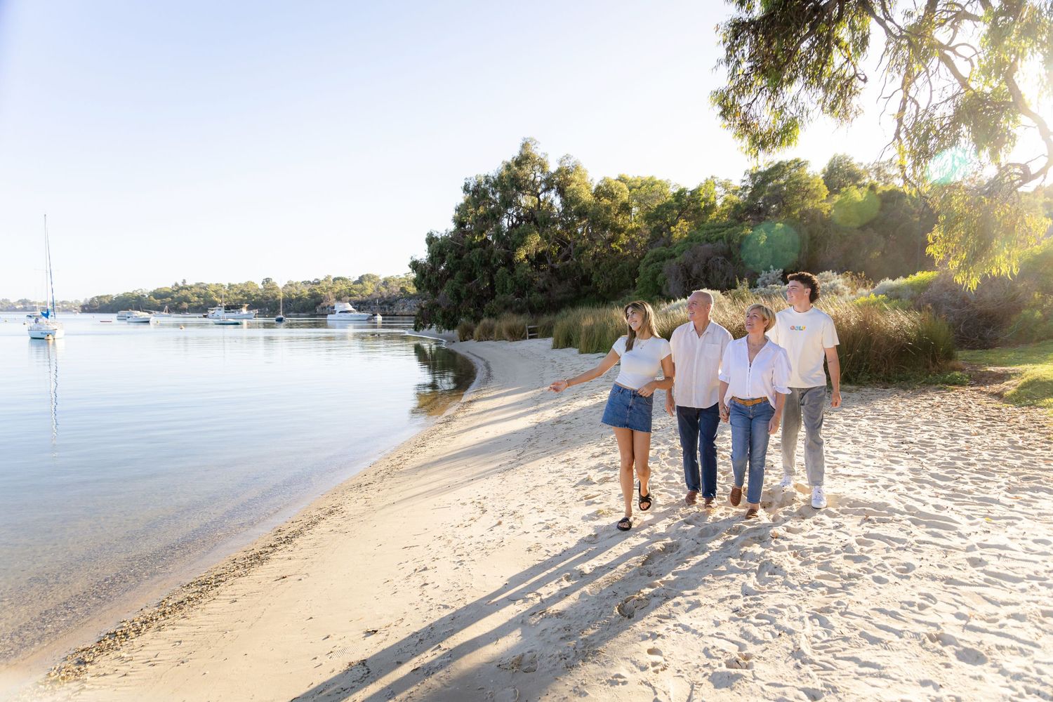 Family walking together along sandy beach shoreline at sunset.