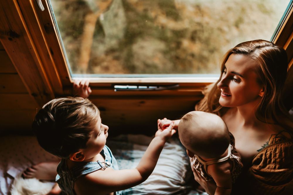Intimate family interaction captured in warm lighting by a cabin window.