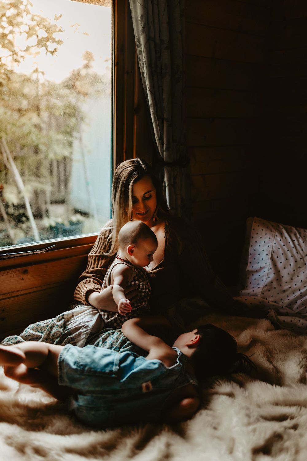Peaceful moment by a cabin window with golden sunlight filtering through trees outside.
