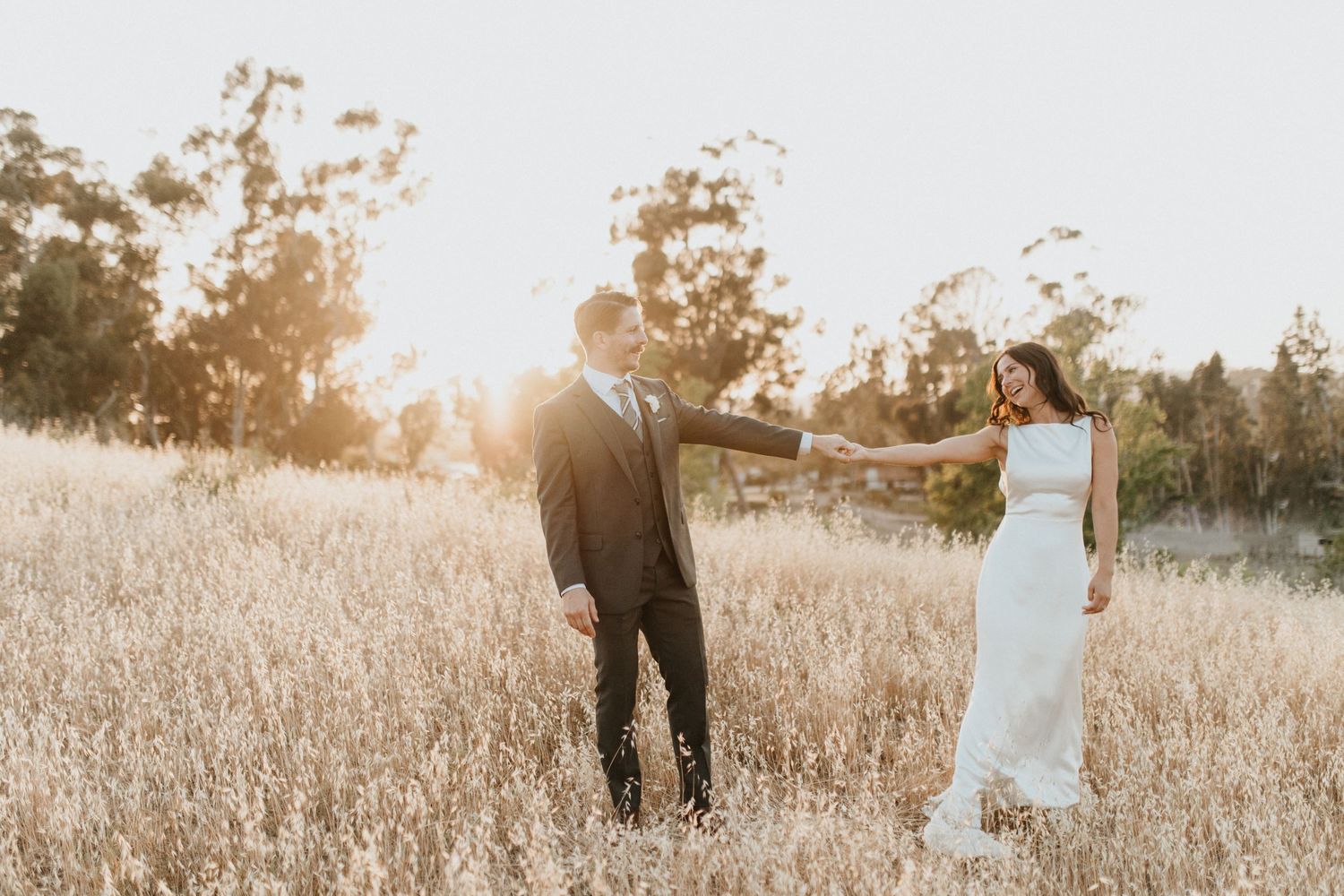 A romantic sunset engagement shoot in a golden field with mountain views.