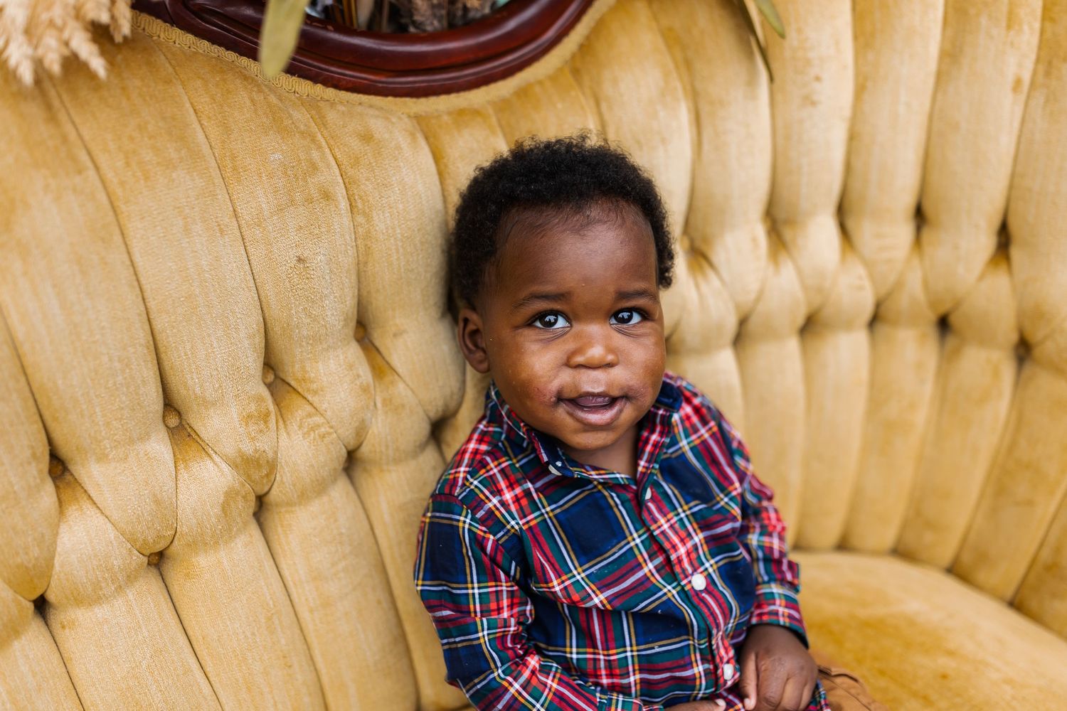 A child sits on a yellow vintage couch during a portrait session.