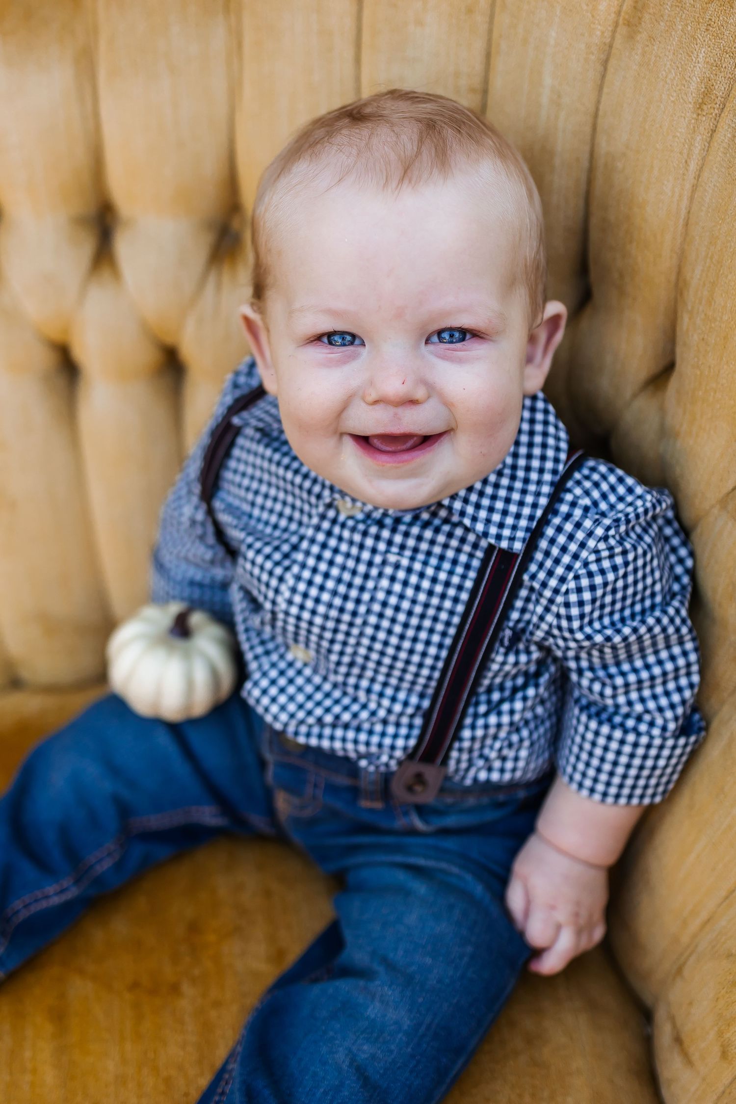 Autumn portrait on gold couch wearing navy and checkered outfit.