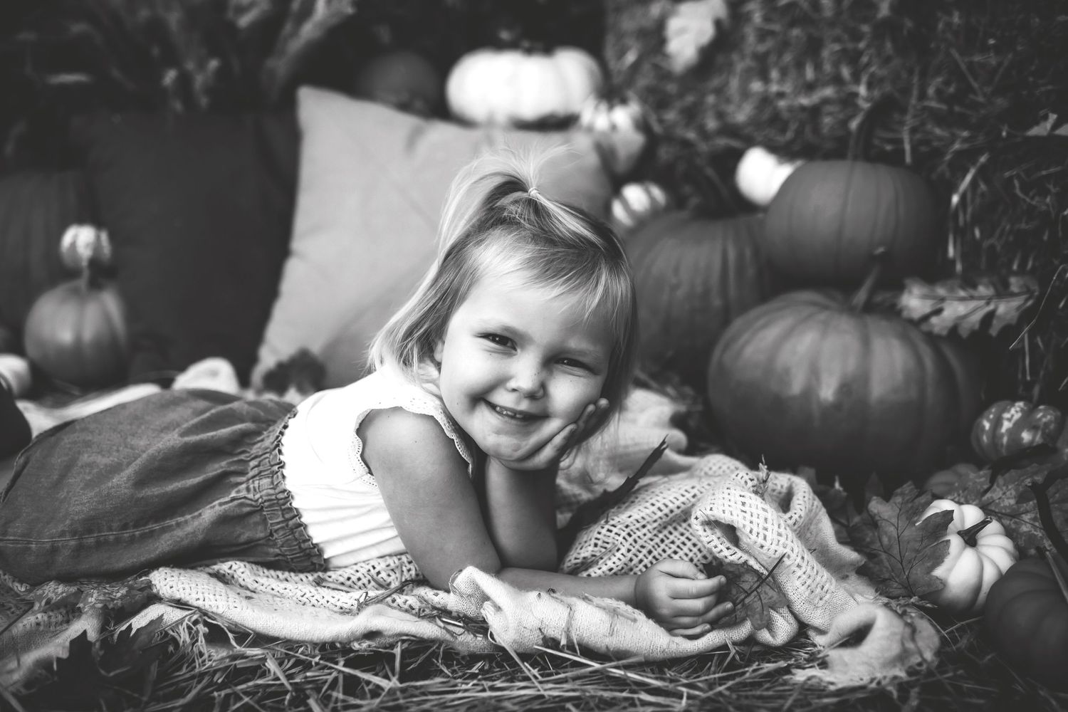 Black and white fall portrait with pumpkins and cozy blankets.