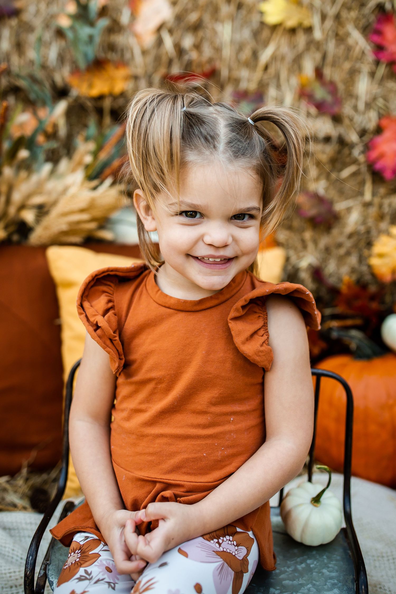 Autumn scene with orange pillows, pumpkins and colorful fall leaves in rustic outdoor setting.