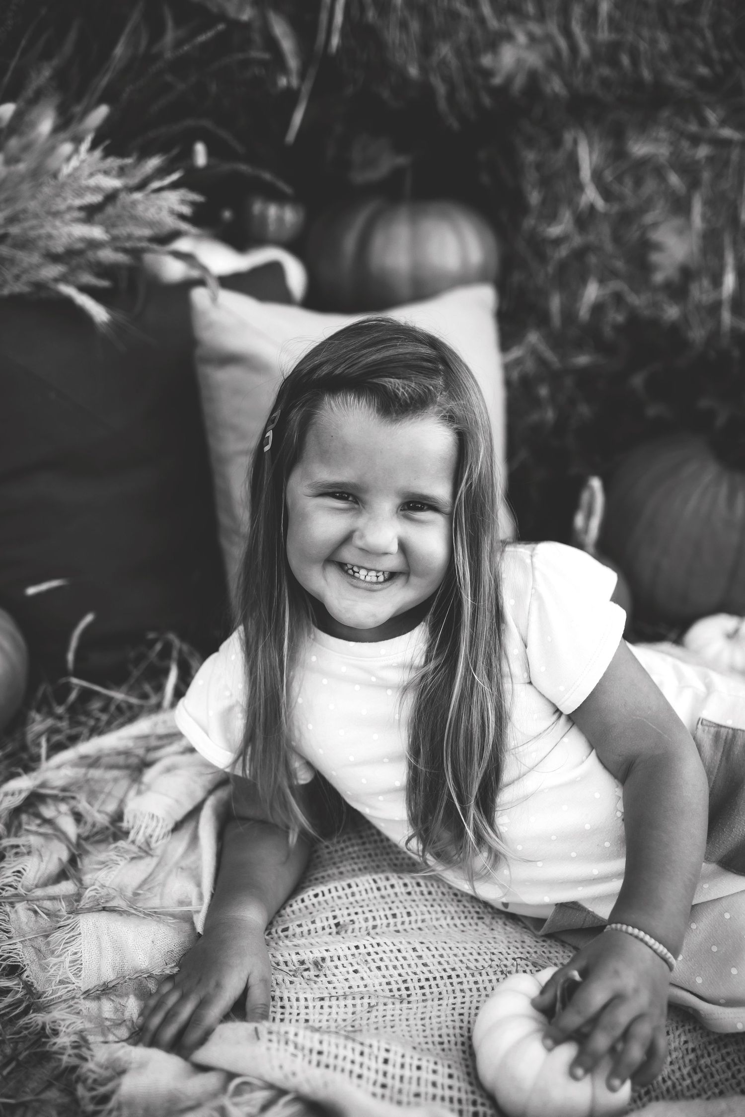 Black and white portrait showcasing joy amid pumpkins and seasonal decor.