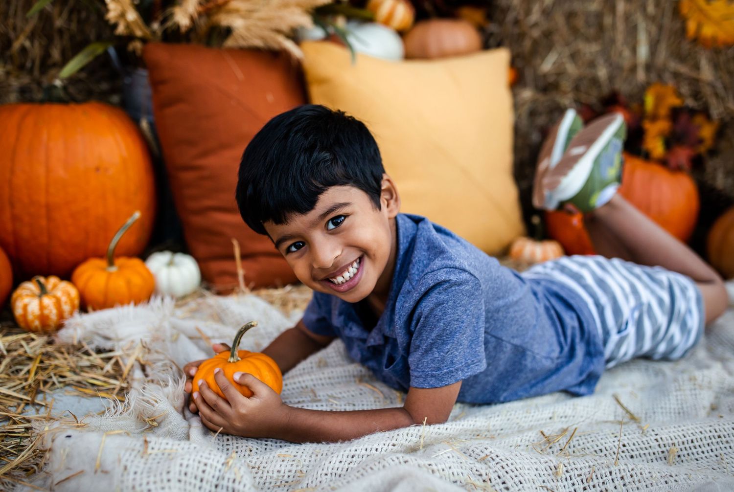 Happy autumn moment captured with orange pumpkins and cozy hay bale setting.