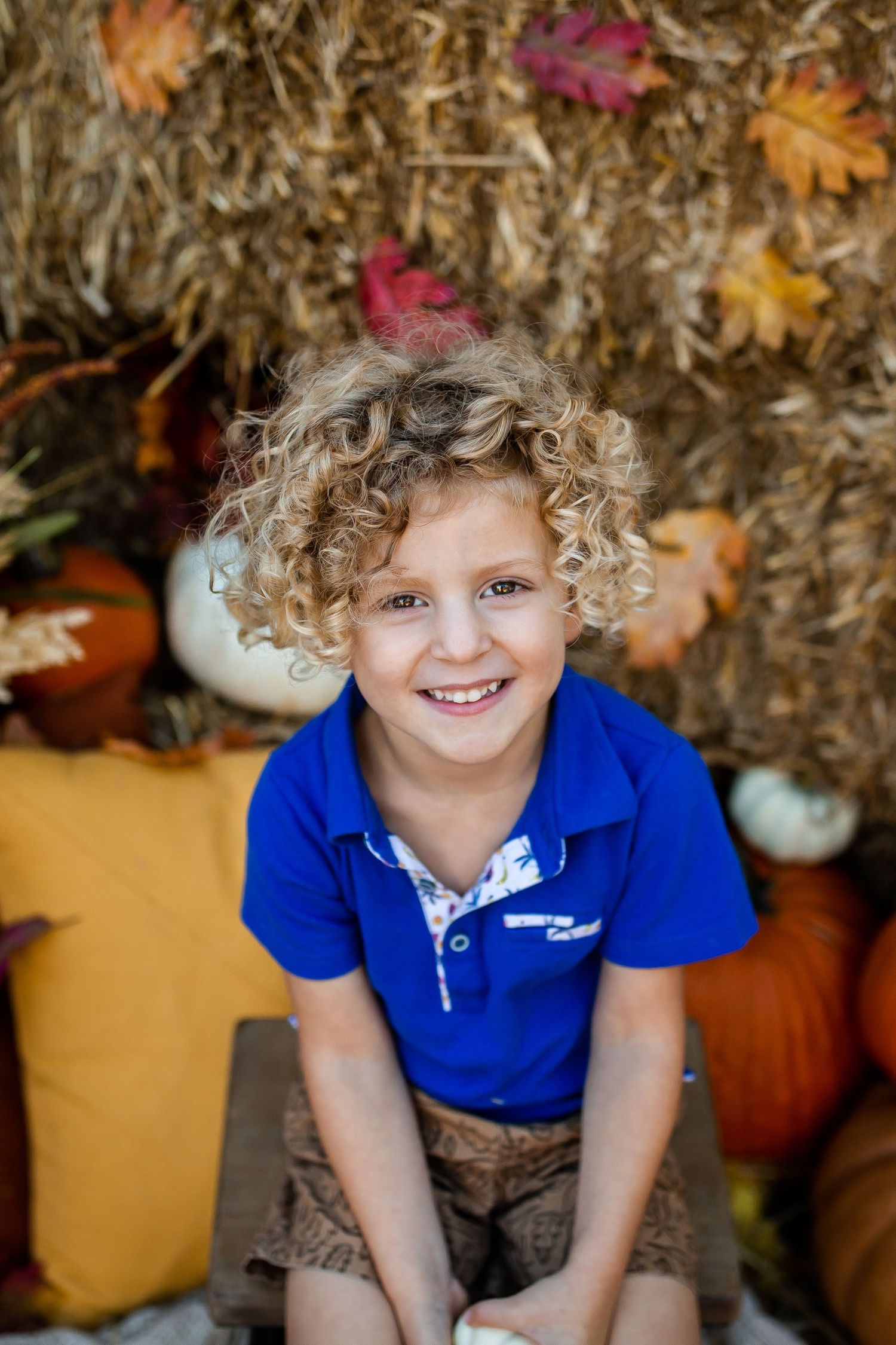 Fall portrait with hay bales and colorful autumn leaves as backdrop.