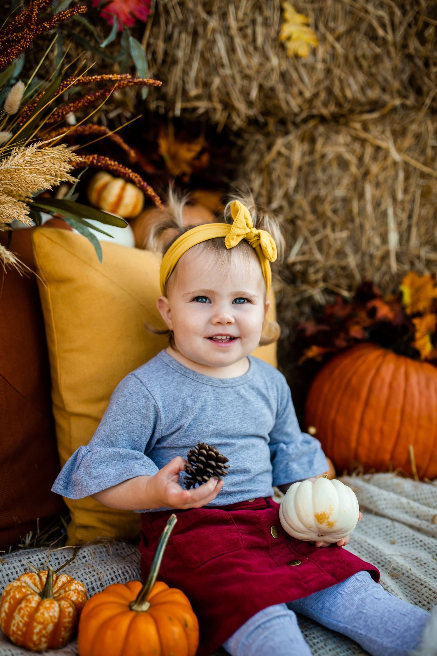 Fall photo setup with white and orange pumpkins against hay bale backdrop.